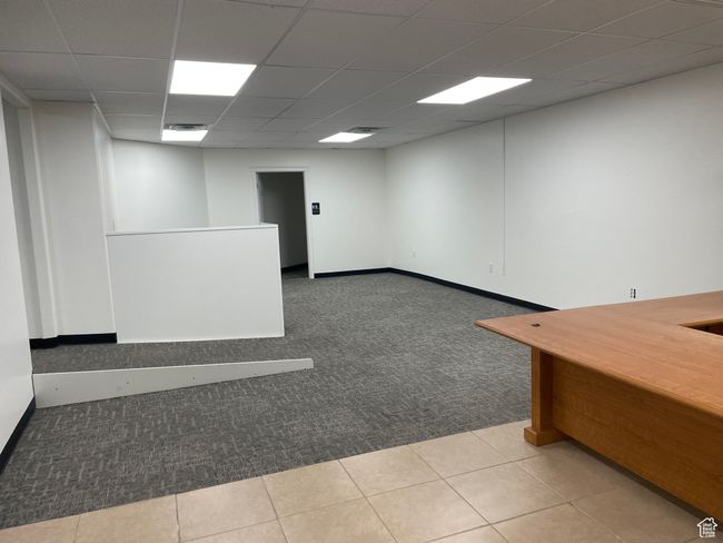 Empty room with a paneled ceiling, carpet floors, and tile patterned flooring | Image 6