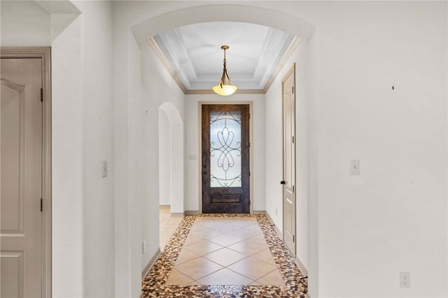 Entryway featuring arched walkways, baseboards, a raised ceiling, and crown molding | Image 5