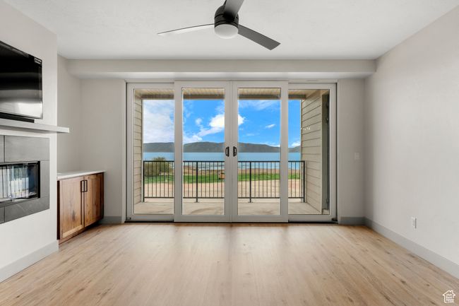 Unfurnished living room with light wood finished floors, a ceiling fan, a glass covered fireplace, and baseboards | Image 11