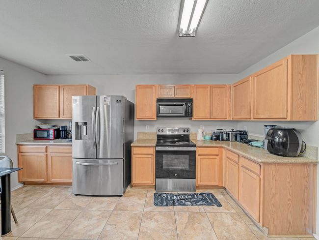 Kitchen featuring stainless steel appliances, light brown cabinetry, light countertops, and a textured ceiling | Image 11