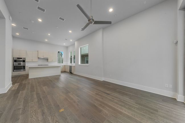 Unfurnished living room featuring a ceiling fan, dark wood-type flooring, visible vents, and recessed lighting | Image 13