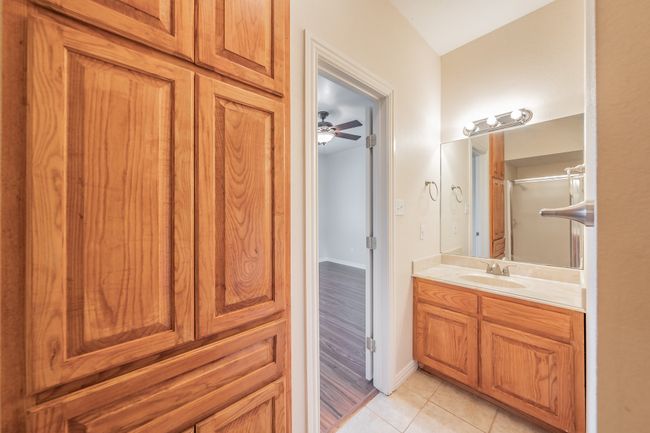 Bathroom with tile patterned floors, vanity, ceiling fan, built in cabinets and a shower | Image 9