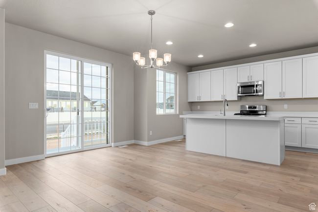 Kitchen with appliances with stainless steel finishes, baseboards, light countertops, a chandelier, and recessed lighting | Image 9