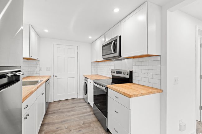 Kitchen with butcher block counters, stainless steel appliances, light wood-type flooring, recessed lighting, and white cabinets | Image 7