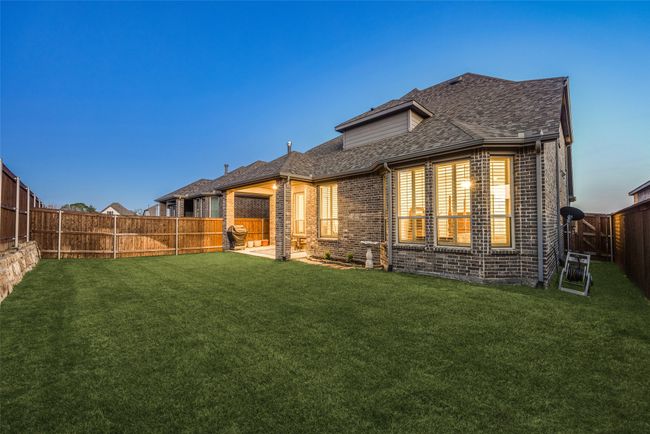 Rear view of house featuring brick siding, a fenced backyard, a lawn, and roof with shingles | Image 34