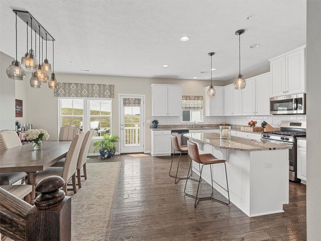 This stunning kitchen is the heart of the home, featuring crisp white cabinetry, granite countertops, and stainless steel appliances for a sleek, modern look. | Image 6