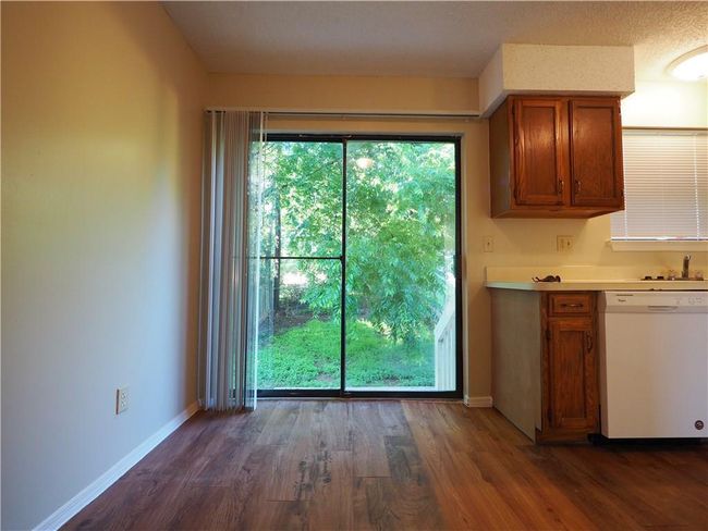 Kitchen featuring white dishwasher, brown cabinetry, dark wood-style floors, light countertops, and baseboards | Image 10