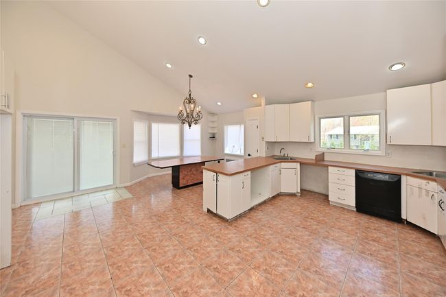 Kitchen with black dishwasher, a peninsula, white cabinets, and a sink | Image 13