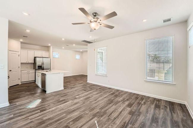 Kitchen featuring backsplash, ceiling fan, open floor plan, light countertops, and stainless steel appliances | Image 6