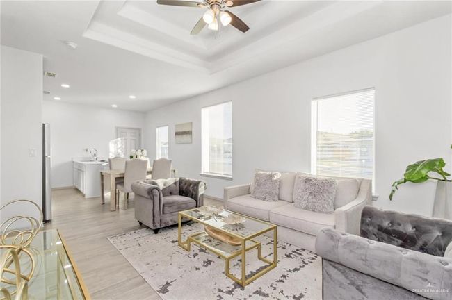 Living area with light wood finished floors, a ceiling fan, recessed lighting, and a raised ceiling | Image 8