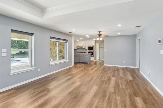 Unfurnished living room with a ceiling fan, light wood-type flooring, baseboards, visible vents, and recessed lighting | Image 10