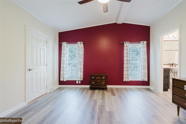 Unfurnished bedroom with wood finished floors, ornamental molding, a ceiling fan, and ensuite bath | Image 11
