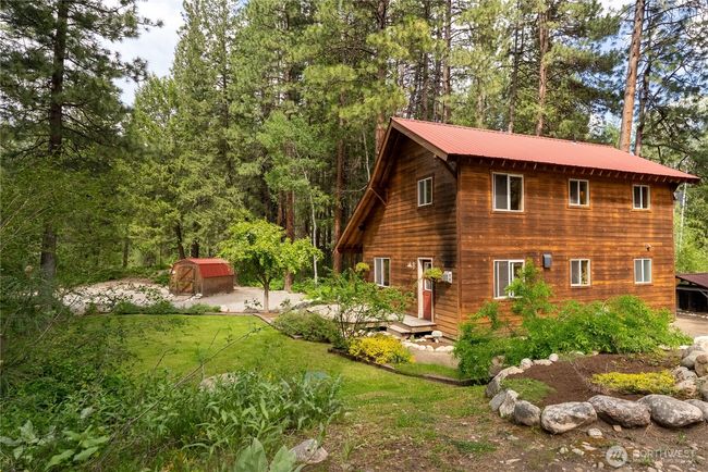 Well-maintained yard with established garden beds and lush lawn. Detached storage shed with matching roof for tools or gear. | Image 39
