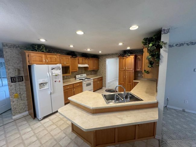 Kitchen featuring kitchen peninsula, sink, and white appliances | Image 6