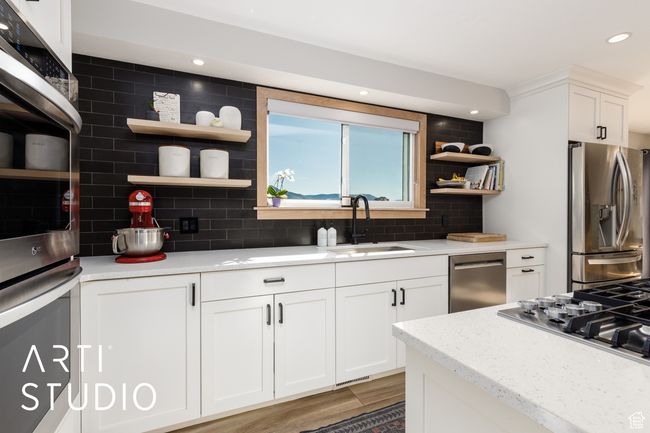 Kitchen with open shelves, appliances with stainless steel finishes, decorative backsplash, and a sink | Image 13