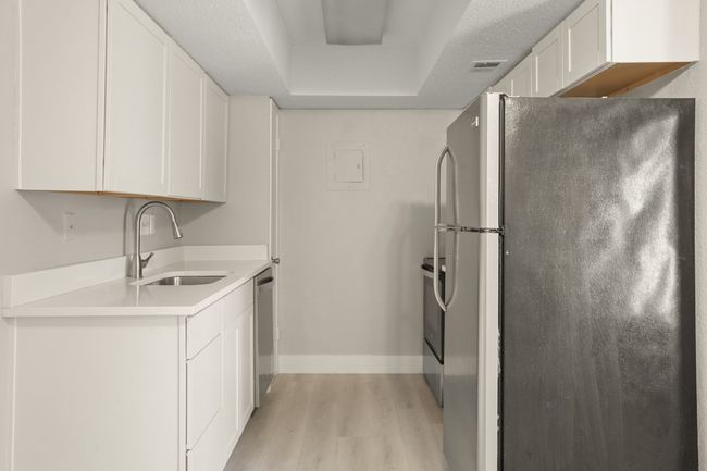 Kitchen featuring stainless steel appliances, light wood finished floors, white cabinetry, and light countertops | Image 5