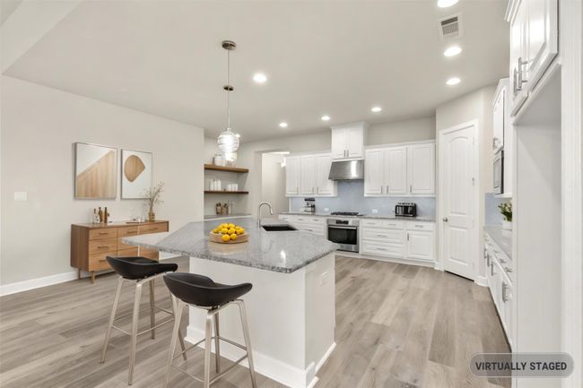 Virtually staged Kitchen with under cabinet range hood, light wood-style floors, a sink, stainless steel oven, and white cabinetry | Image 8