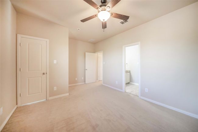 Unfurnished bedroom featuring light carpet, connected bathroom, and ceiling fan | Image 27