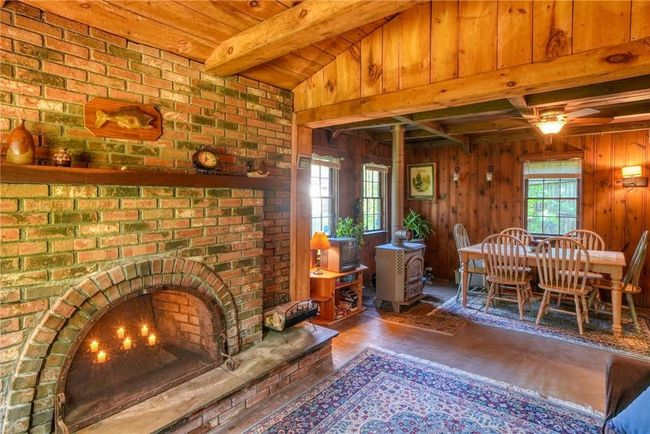 Living room with ceiling fan, wood walls, lofted ceiling, and brick wall | Image 7