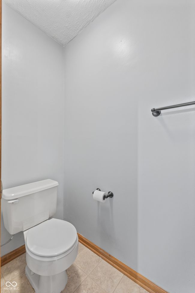 bathroom with toilet, baseboards, a textured ceiling, and tile patterned floors | Image 32