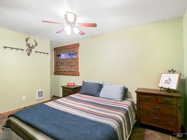 Bedroom with a textured ceiling, a ceiling fan, and dark tile patterned flooring | Image 7