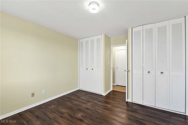 Unfurnished bedroom featuring dark wood-style floors, baseboards, and multiple closets | Image 20