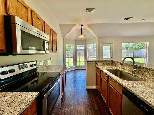 Kitchen with stainless steel appliances, dark wood-type flooring, healthy amount of natural light, and brown cabinetry | Image 7