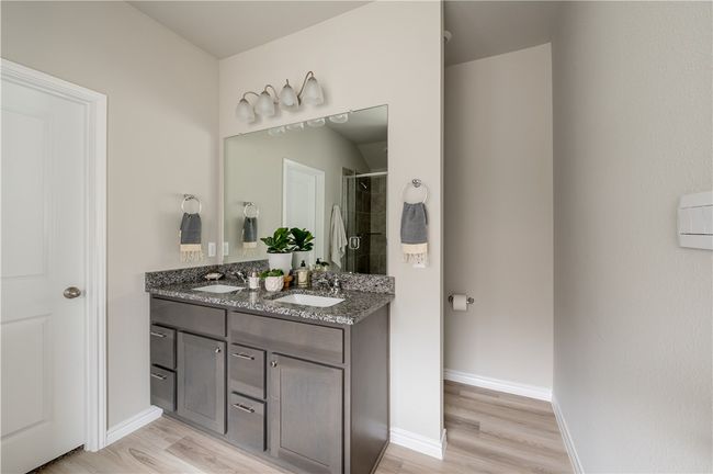 Full bathroom featuring double vanity, tiled shower, wood finished floors, and a sink | Image 12