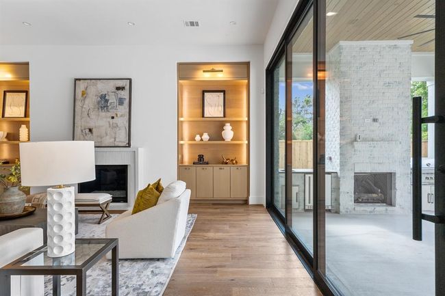 This living space is enhanced by oversized California sliding doors that flood the room with natural light and provide a seamless connection to the outdoors. The custom plastered fireplace serves as a striking focal point, adding warmth and a touch of modern elegance to the room. | Image 20