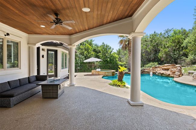 View of patio with an outdoor living space with a fire pit, ceiling fan, and a pool with connected hot tub | Image 36