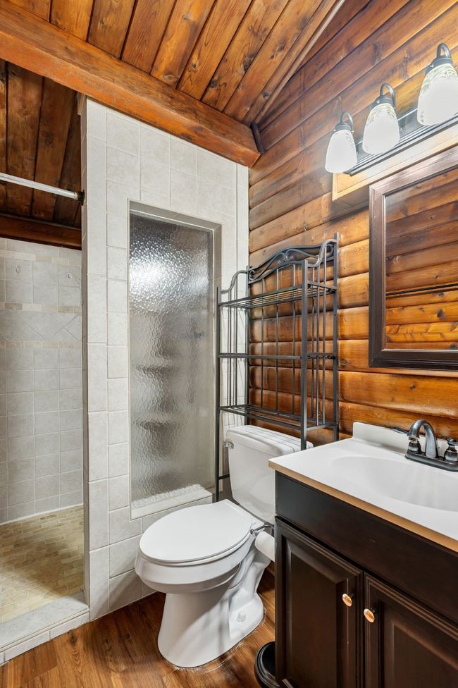 Bathroom featuring a shower stall, vanity, wood finished floors, lofted ceiling, and wooden ceiling | Image 15