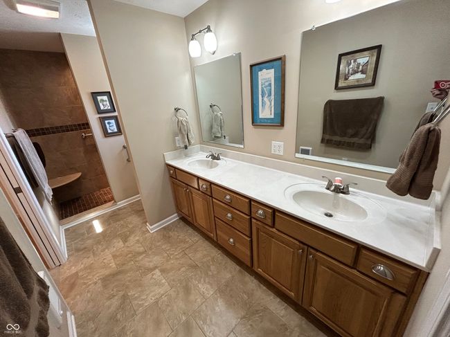 full bathroom with baseboards, double vanity, a walk in shower, and a sink | Image 14