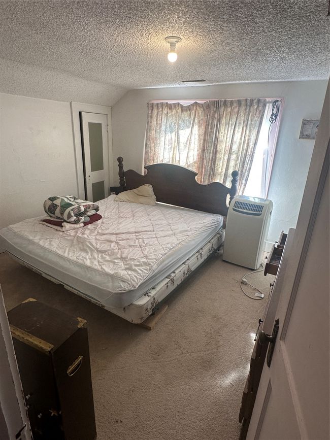 Carpeted bedroom featuring a textured ceiling and vaulted ceiling | Image 19
