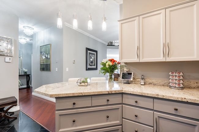 Kitchen featuring gray cabinetry, pendant lighting, ornamental molding, light stone counters, and a peninsula | Image 5