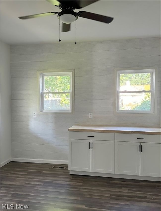 Empty room with a healthy amount of sunlight, ceiling fan, and dark hardwood / wood-style flooring | Image 6