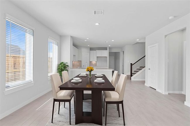 Start your day off right with a cup of coffee sitting with your family in this lovely dining area! Featuring large windows with blinds, custom neutral paint, wood look tile flooring, recessed lighting, and high ceilings! | Image 7