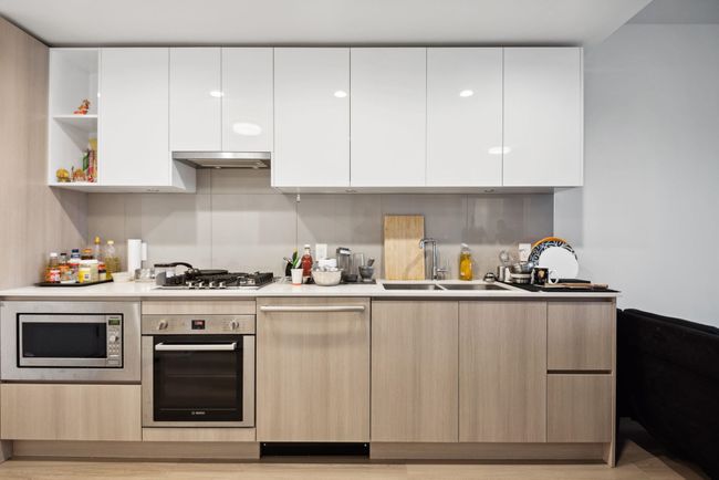 Kitchen featuring under cabinet range hood, modern cabinets, a sink, and stainless steel appliances | Image 7