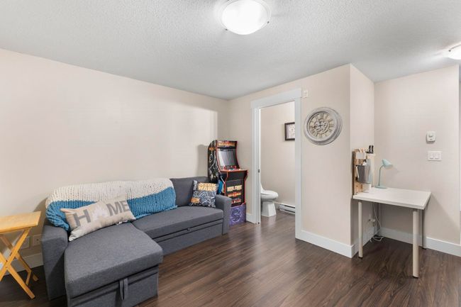 Living room with a baseboard radiator, baseboards, dark wood-style flooring, and a textured ceiling | Image 9