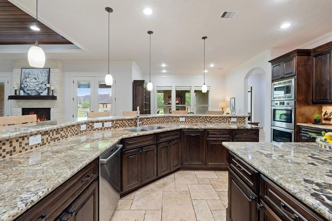 Four pendant lights illuminate the Breakfast Bar and expansive countertop space. The undermount, dual-basin, stainless steel sink comes equipped with a pull-down faucet and soap dispenser. | Image 20