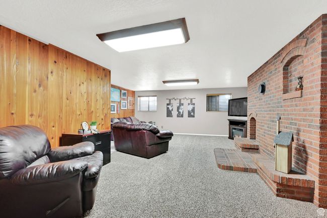 Carpeted living room with a brick fireplace and wooden walls | Image 26