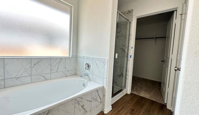 Bathroom featuring wood finished floors, healthy amount of natural light, a marble finish shower, and a bath | Image 8