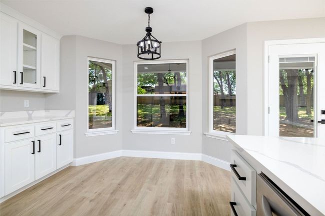 Unfurnished dining area with light wood-style flooring, a chandelier, and healthy amount of natural light | Image 22