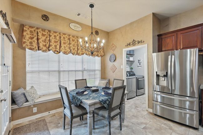 Dining area featuring washing machine and clothes dryer, a chandelier, baseboards, and light tile patterned floors | Image 12
