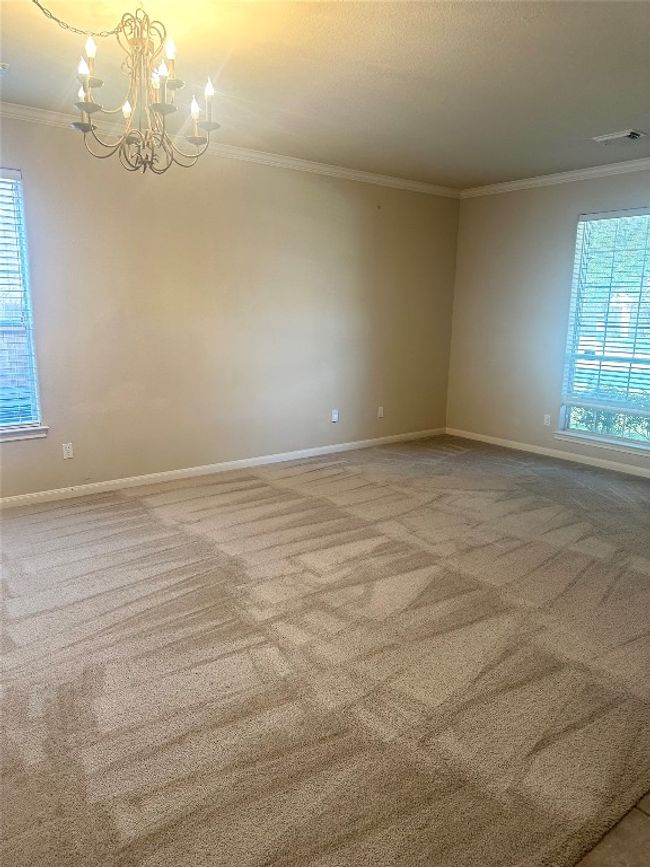 Carpeted spare room featuring crown molding and a chandelier | Image 10