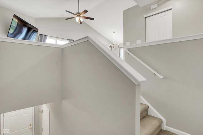 stairway with a chandelier, lofted ceiling, and a ceiling fan | Image 7