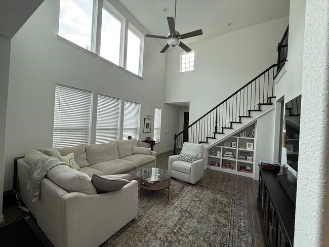 Living room with a high ceiling, ceiling fan, stairway, and dark wood-type flooring | Image 4