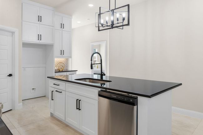 Kitchen with a sink, dark countertops, dishwasher, and an island with sink | Image 9