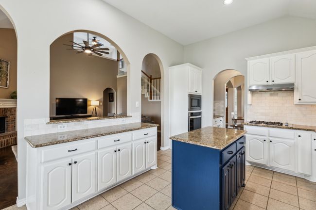 Kitchen with under cabinet range hood, arched walkways, ceiling fan, and stainless steel appliances | Image 11