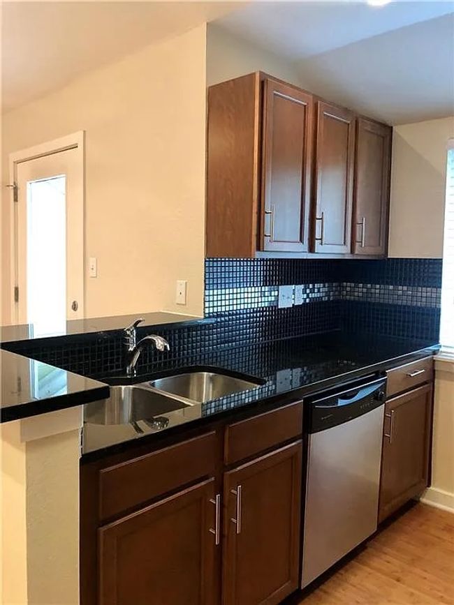 Kitchen with dishwasher, dark countertops, decorative backsplash, light wood finished floors, and a peninsula | Image 4