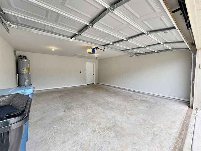 Garage featuring a garage door opener and electric water heater | Image 16